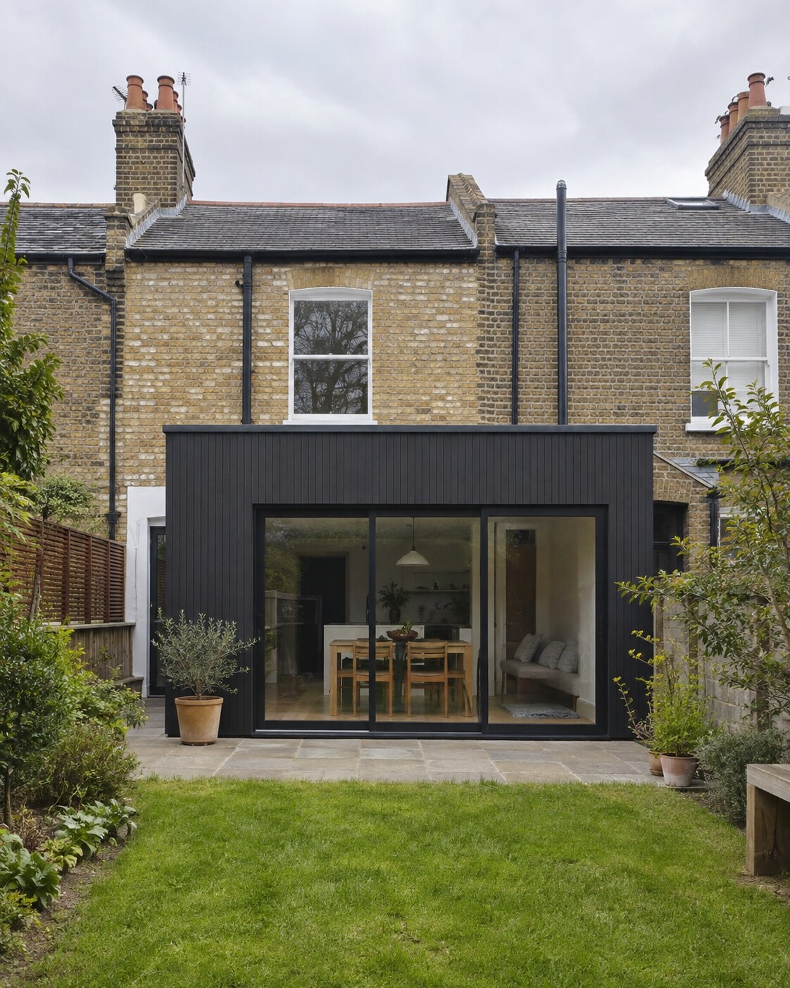 Charcoal-clad flat-roof extension opening onto a narrow garden
